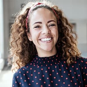 woman in red polka doted blue shirt with curly hair smiling